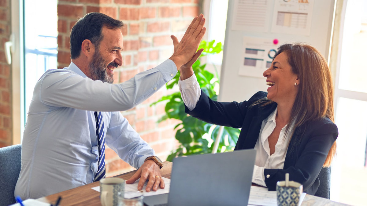  A man and a woman high fiving in the office