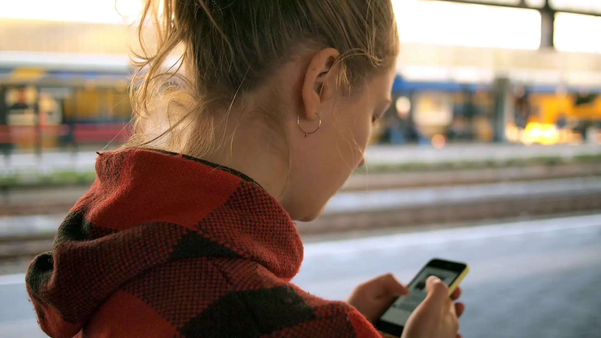 A woman on her phone while walking outside, showing one of the factors to consider when creating a mobile SEO strategy